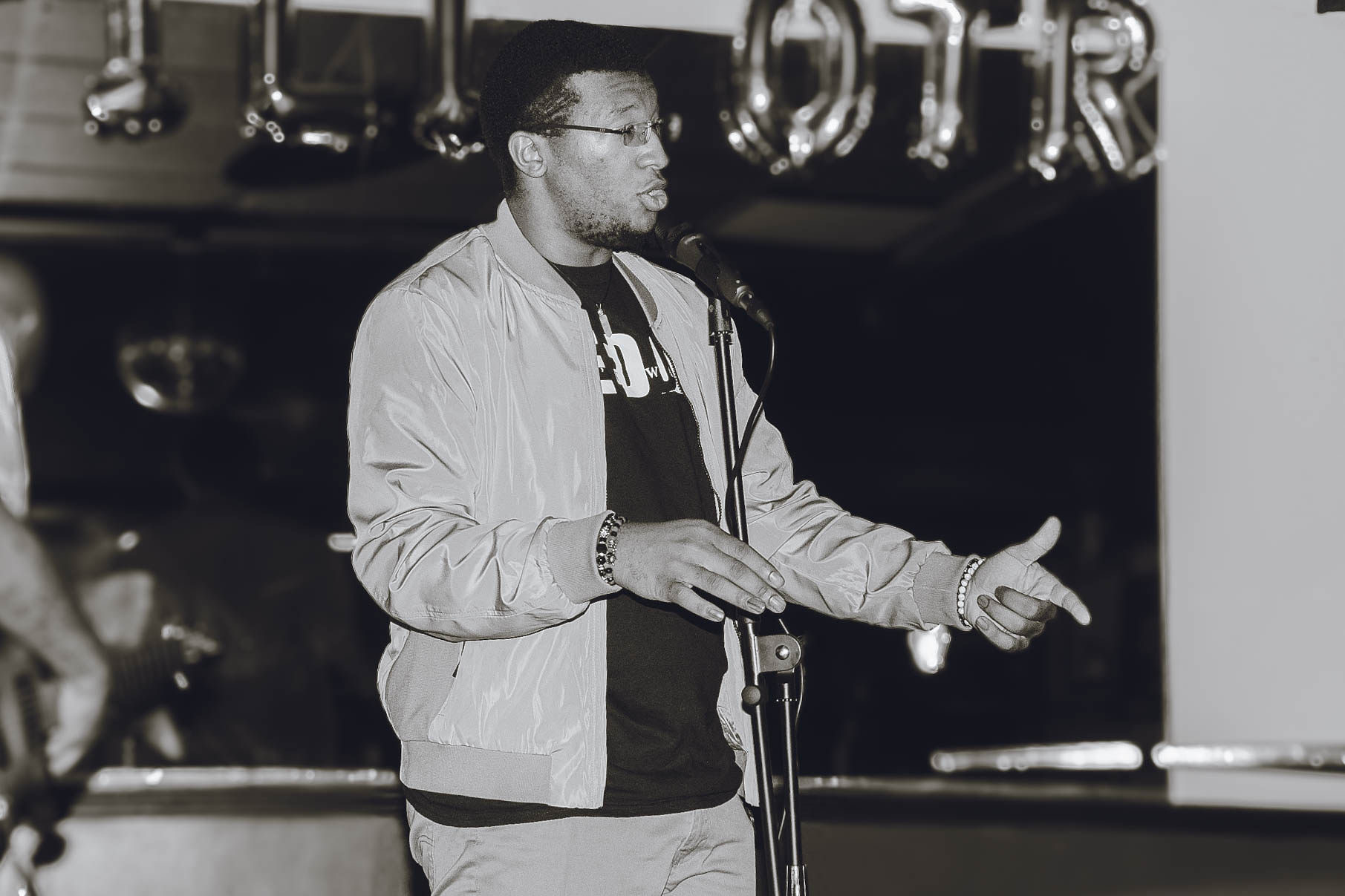 Black and white image of Valden Campbell performing at a microphone.