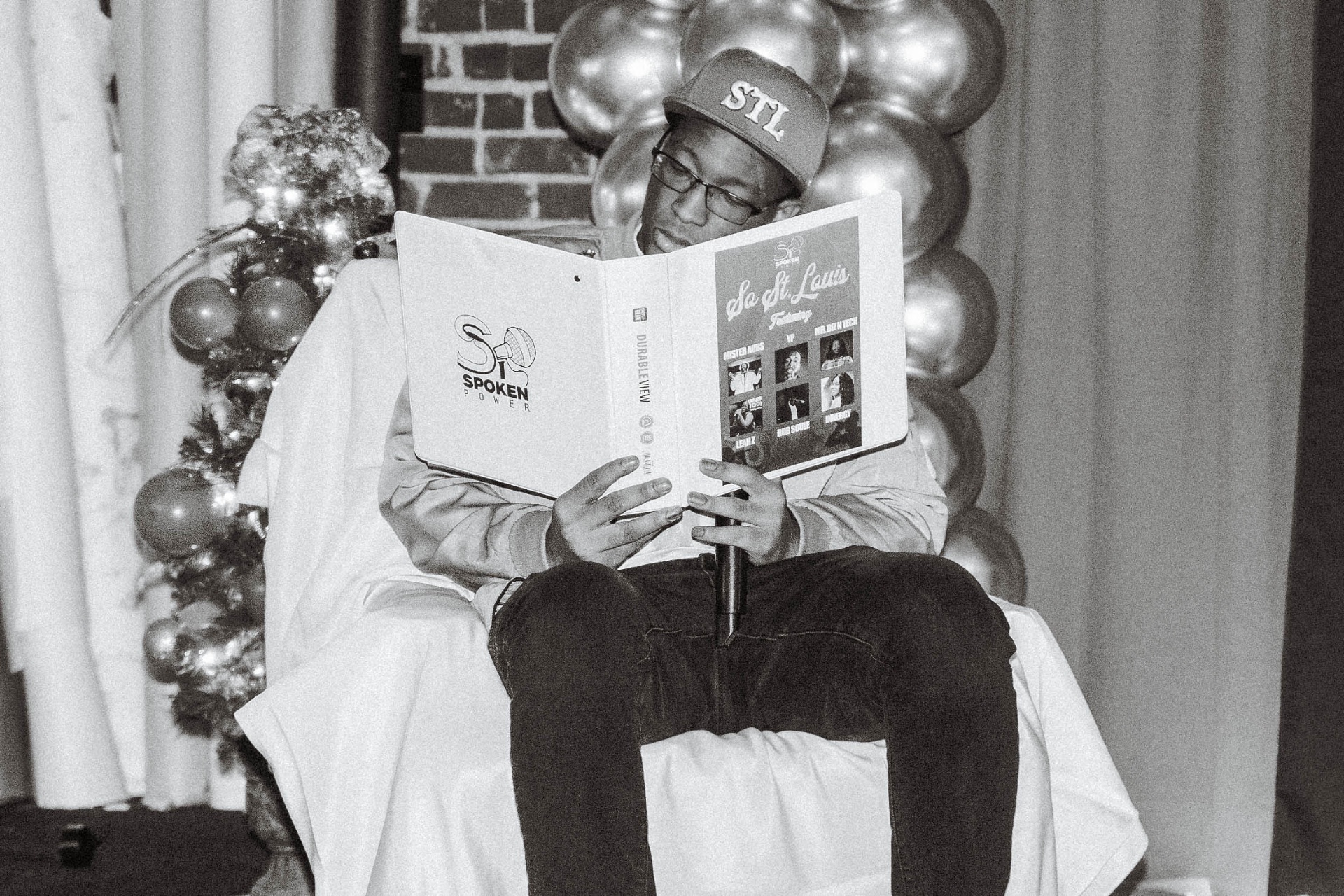 Valden Campbell reading from a binder during an event.